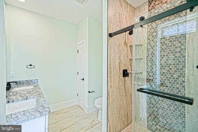 bathroom with vanity, toilet, and a shower with door