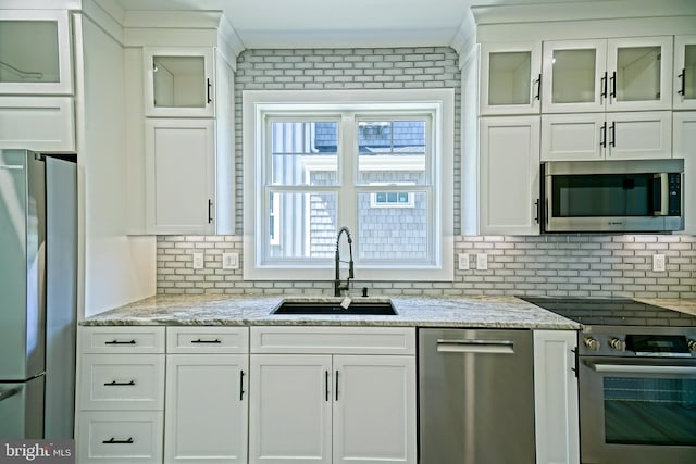 kitchen with appliances with stainless steel finishes, backsplash, white cabinetry, and sink