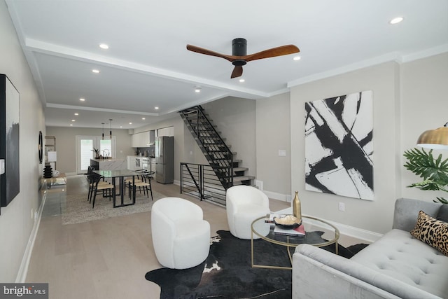 living room with light hardwood / wood-style flooring, ceiling fan, and ornamental molding