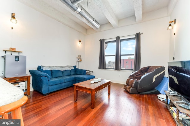 living room featuring beam ceiling, dark wood-type flooring, and a textured ceiling