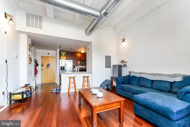 living room featuring electric panel, dark wood-type flooring, and a high ceiling