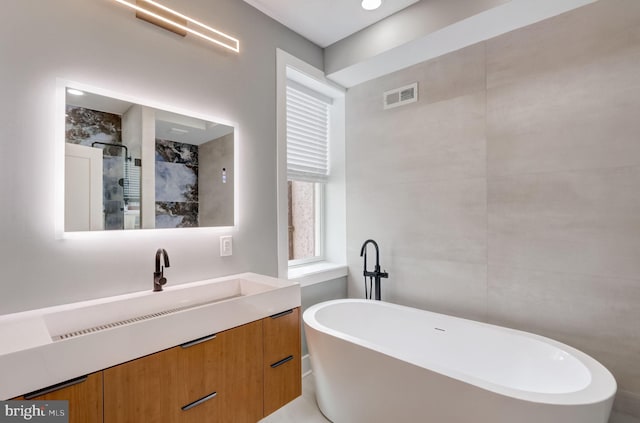 bathroom with vanity and shower with separate bathtub