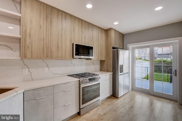 kitchen featuring decorative backsplash, light hardwood / wood-style floors, light brown cabinetry, and appliances with stainless steel finishes