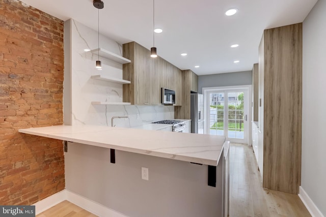 kitchen featuring stainless steel appliances, light hardwood / wood-style flooring, kitchen peninsula, pendant lighting, and a breakfast bar area