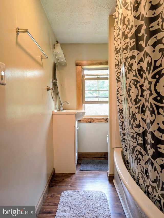 bathroom featuring bathing tub / shower combination, hardwood / wood-style floors, vanity, and a textured ceiling