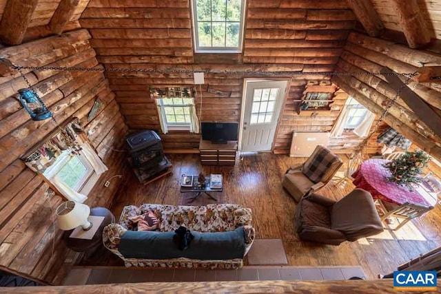 living room with beam ceiling, hardwood / wood-style floors, and log walls