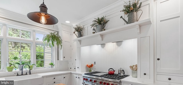 kitchen with decorative light fixtures, white cabinetry, sink, and range