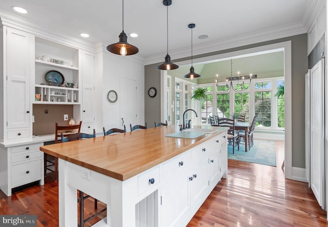 kitchen with white cabinets, built in shelves, a kitchen bar, and an island with sink