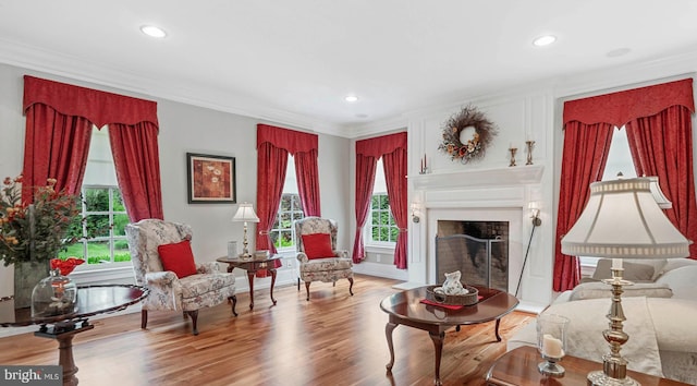 sitting room with a wealth of natural light, hardwood / wood-style flooring, and ornamental molding