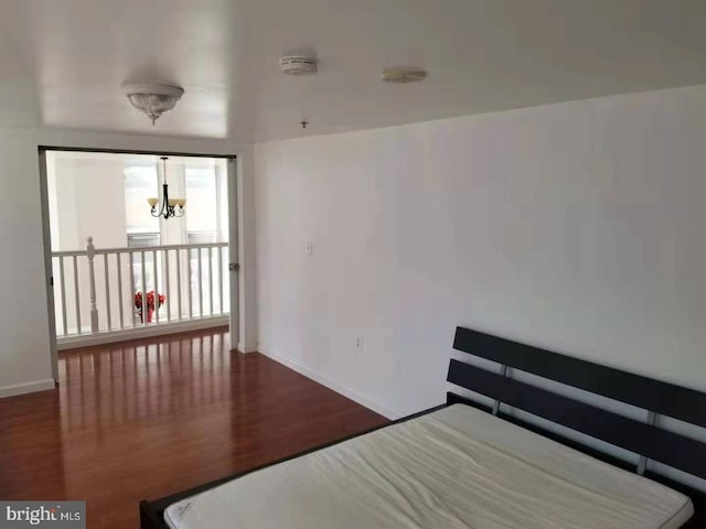 bedroom with a chandelier and dark wood-type flooring