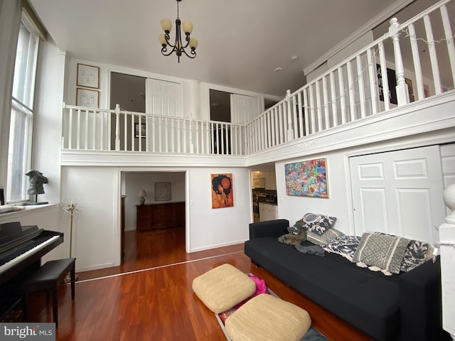 living room with dark hardwood / wood-style flooring, a towering ceiling, and an inviting chandelier