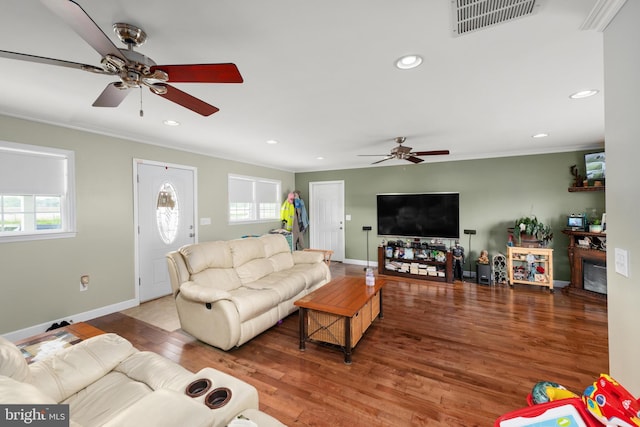 living room featuring a fireplace, wood-type flooring, and ornamental molding