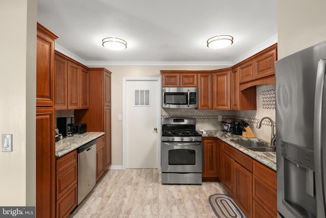 kitchen with backsplash, light stone counters, sink, and appliances with stainless steel finishes