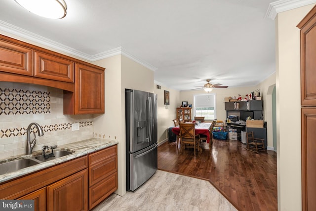 kitchen with sink, light hardwood / wood-style flooring, stainless steel fridge, crown molding, and decorative backsplash