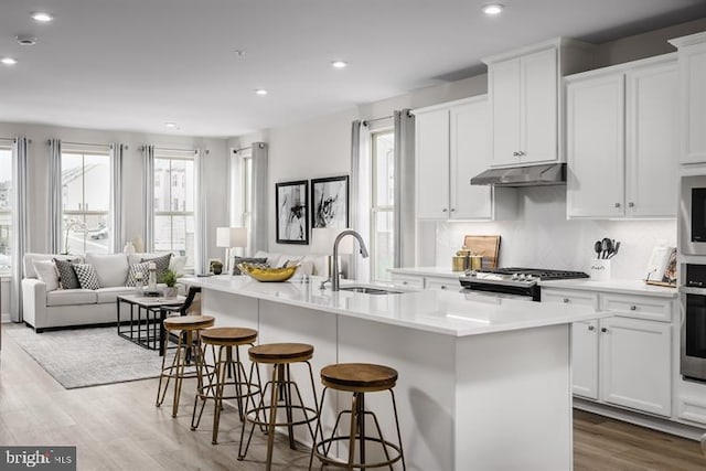 kitchen with appliances with stainless steel finishes, white cabinetry, a kitchen island with sink, and sink