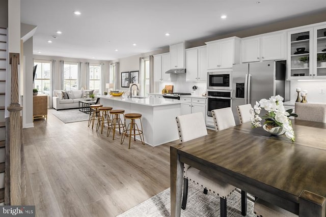 kitchen with white cabinets, an island with sink, appliances with stainless steel finishes, and a kitchen breakfast bar