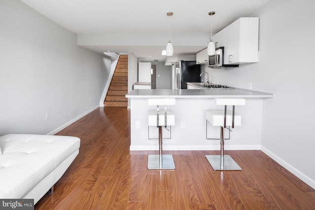 kitchen with white cabinets, a breakfast bar, kitchen peninsula, and appliances with stainless steel finishes