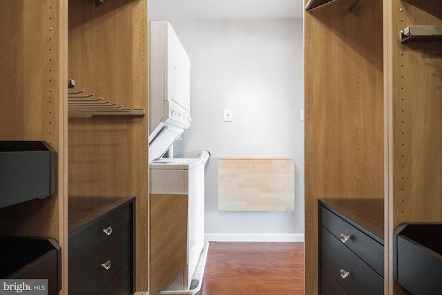 walk in closet with stacked washer / dryer and dark hardwood / wood-style flooring