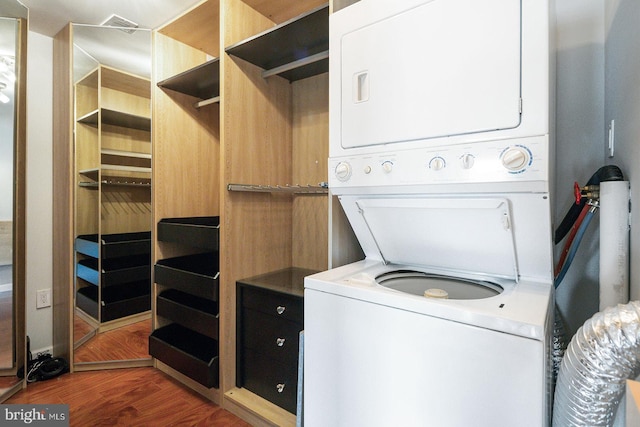 laundry room with dark hardwood / wood-style floors and stacked washer / drying machine