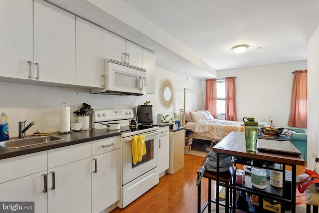 kitchen featuring light hardwood / wood-style flooring, white cabinets, white appliances, and sink