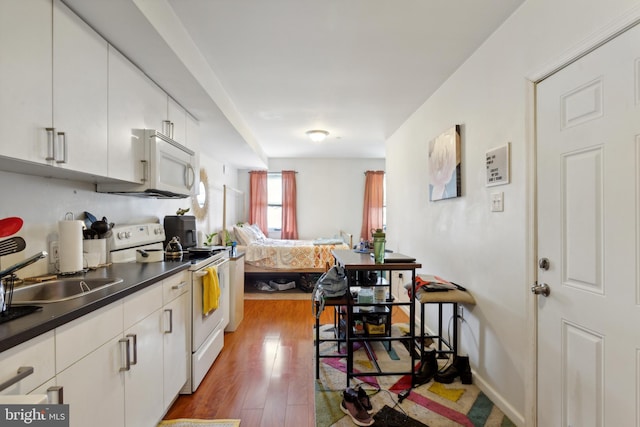 kitchen with hardwood / wood-style floors, white cabinetry, white appliances, and sink