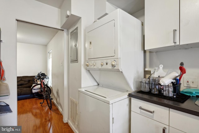 washroom featuring hardwood / wood-style flooring and stacked washer and clothes dryer