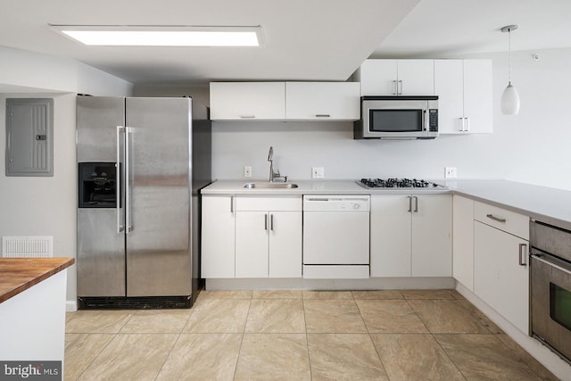 kitchen featuring appliances with stainless steel finishes, sink, electric panel, white cabinetry, and hanging light fixtures