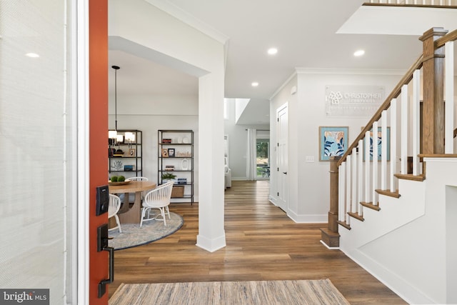 foyer featuring crown molding, wood-type flooring, and an inviting chandelier