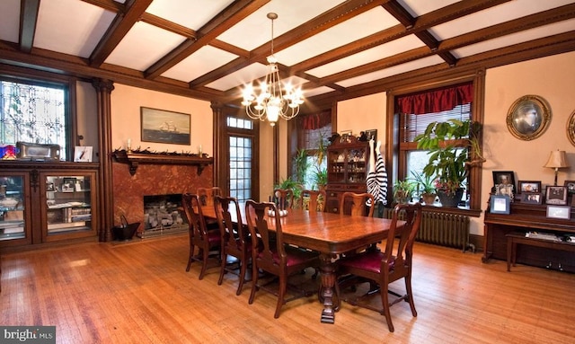 dining room with beam ceiling, radiator heating unit, light hardwood / wood-style flooring, a notable chandelier, and a fireplace