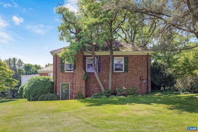 view of side of home featuring brick siding and a yard