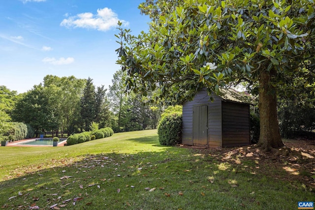 view of yard with an outbuilding, a storage unit, and an outdoor pool