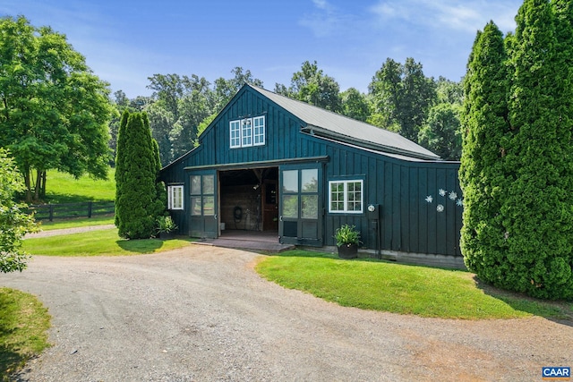 view of front facade featuring an outbuilding, a detached garage, driveway, a front lawn, and board and batten siding