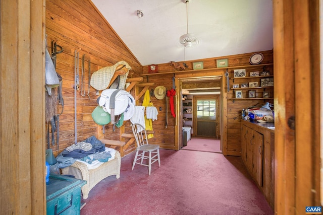 interior space with wood walls, carpet, and vaulted ceiling