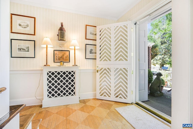 foyer featuring light wood finished floors, ornamental molding, and baseboards