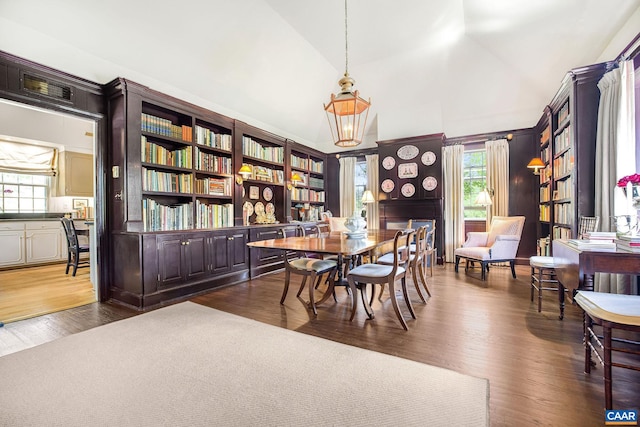 dining area with dark wood-type flooring and vaulted ceiling