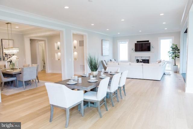 dining space featuring a fireplace, crown molding, and light hardwood / wood-style floors