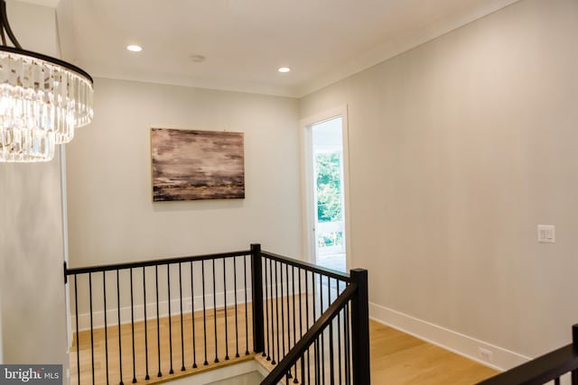 hall featuring light hardwood / wood-style floors, ornamental molding, and a chandelier