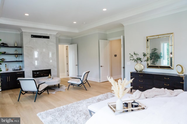 bedroom with light wood-type flooring, a premium fireplace, and ornamental molding