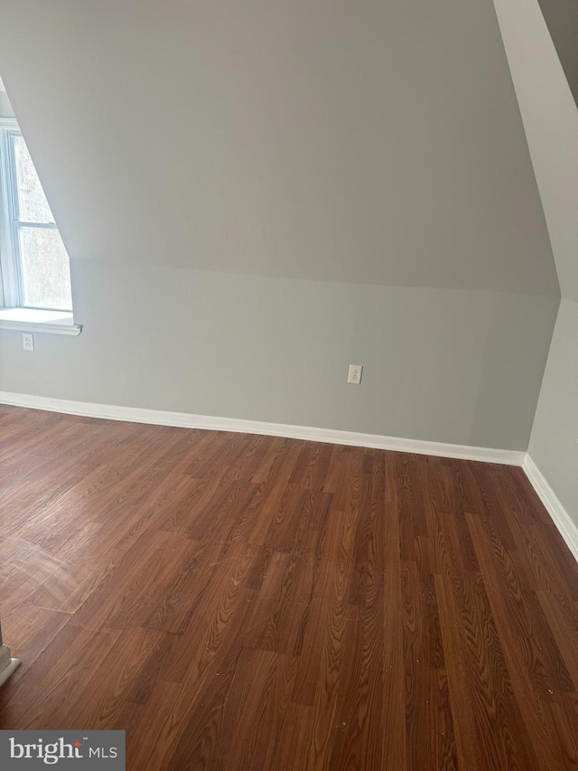 bonus room with dark wood-type flooring and vaulted ceiling