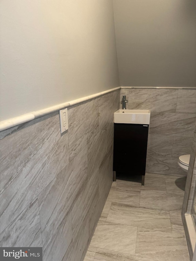 bathroom with vanity, toilet, and tile walls