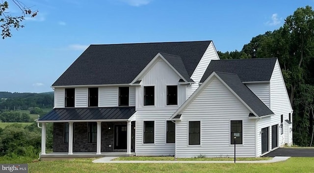 modern farmhouse with a porch, a garage, and a front lawn