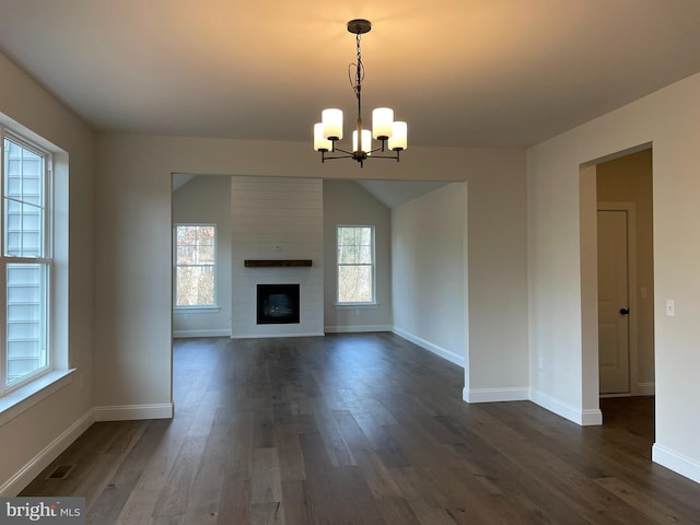 unfurnished living room with a fireplace, dark hardwood / wood-style flooring, a chandelier, and a wealth of natural light