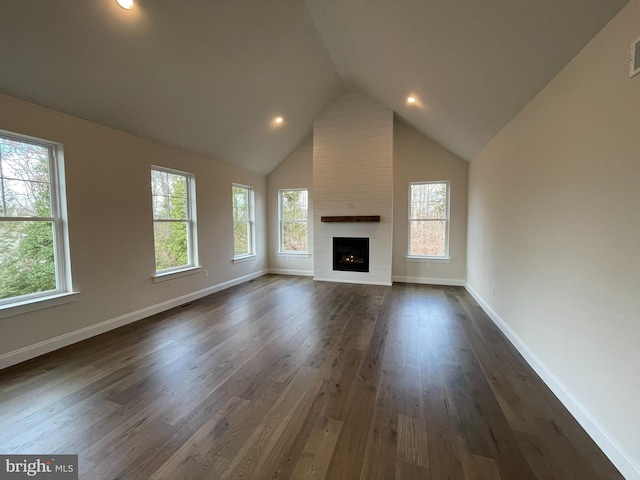 unfurnished living room featuring a large fireplace, dark hardwood / wood-style flooring, and a healthy amount of sunlight