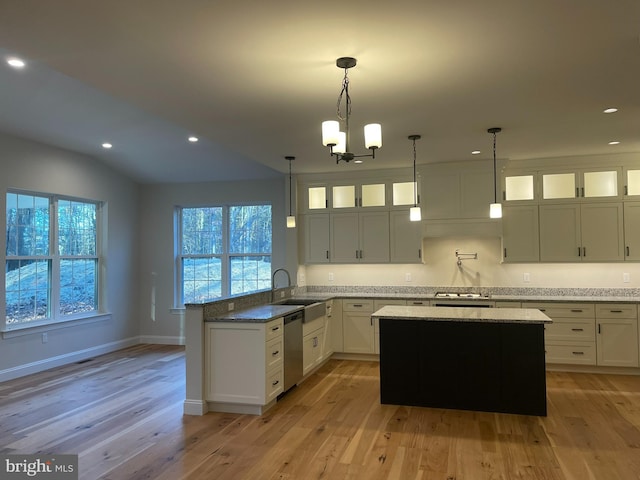 kitchen featuring light stone counters, stainless steel appliances, hanging light fixtures, and light hardwood / wood-style flooring