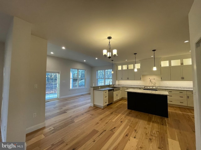 kitchen featuring light wood-type flooring, white cabinetry, a kitchen island, and sink