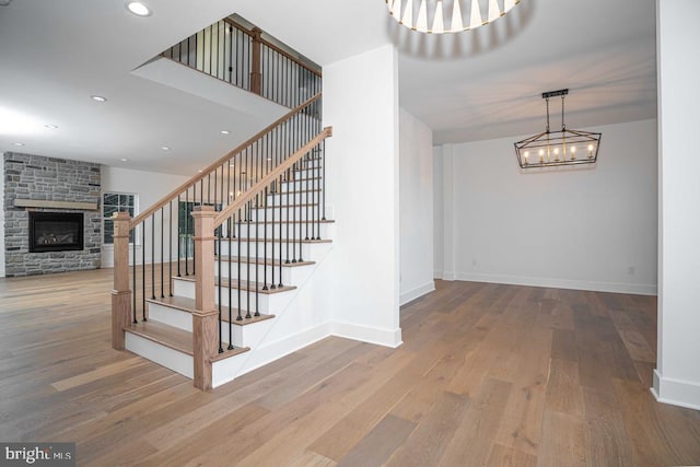 staircase featuring wood-type flooring and a stone fireplace