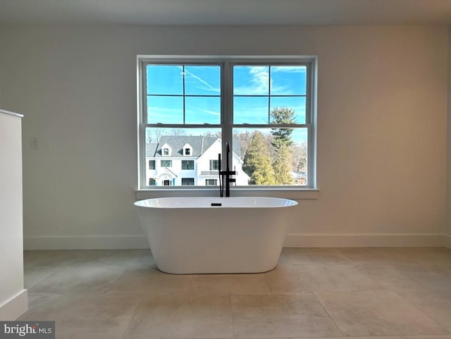 bathroom with tile patterned floors, a bathtub, and a healthy amount of sunlight