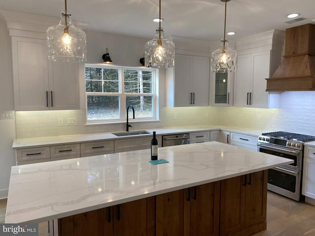 kitchen with appliances with stainless steel finishes, custom exhaust hood, a kitchen island, sink, and white cabinetry