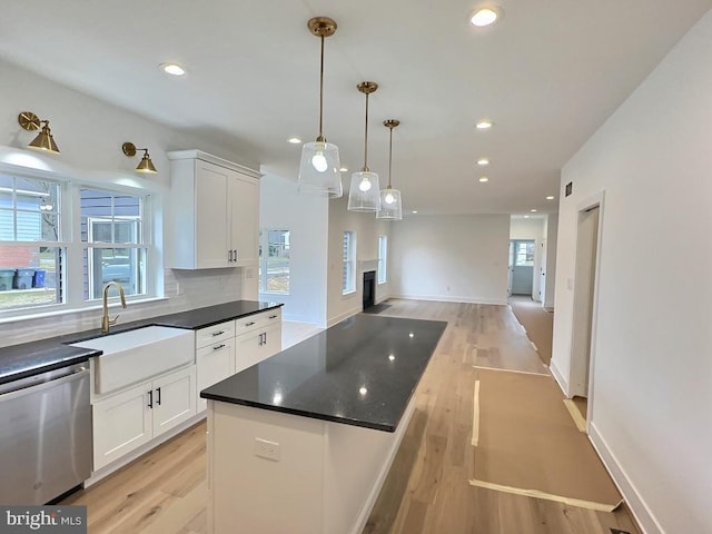 kitchen featuring stainless steel dishwasher, plenty of natural light, white cabinetry, and sink