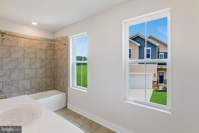 bathroom featuring tile patterned floors, a healthy amount of sunlight, sink, and tiled shower / bath